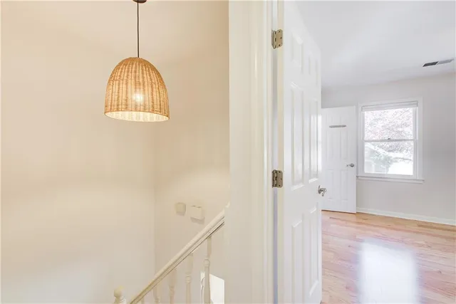 a view of a hallway to a bedroom with wooden floor and windows