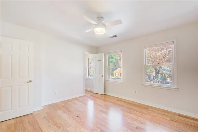 an empty room with wooden floor and windows