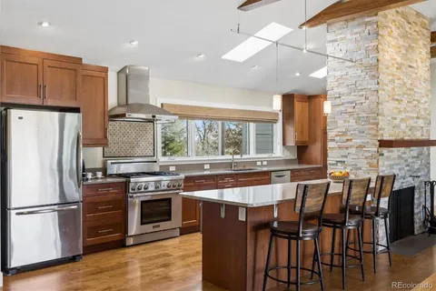 a kitchen with stainless steel appliances a stove a sink a dining table and chairs