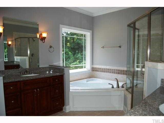 6912 Johnson Mill Road Bahama, NC 27503 - Photo 6 of 12 a bathroom with a granite countertop sink a bathtub a mirror and a shower