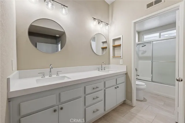 a bathroom with a double vanity sink mirror and toilet