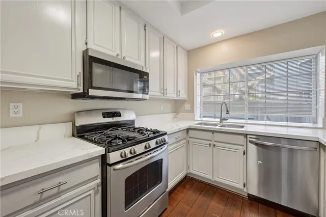 a kitchen with cabinets appliances a sink and a window