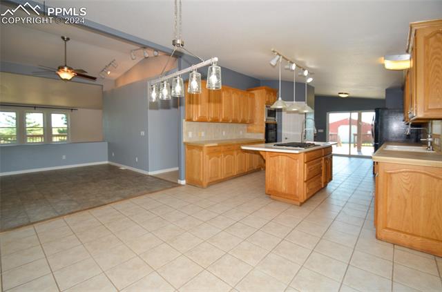 34115 Big Springs Road Yoder, CO 80864 - Photo 7 of 35 Kitchen with ceiling fan, pendant lighting, light tile floors, a kitchen island, and tasteful backsplash