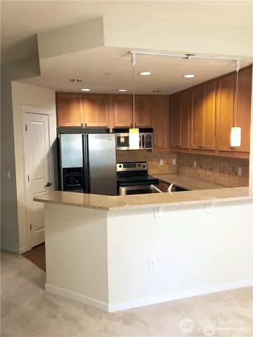 a kitchen with stainless steel appliances granite countertop a sink a stove and a refrigerator