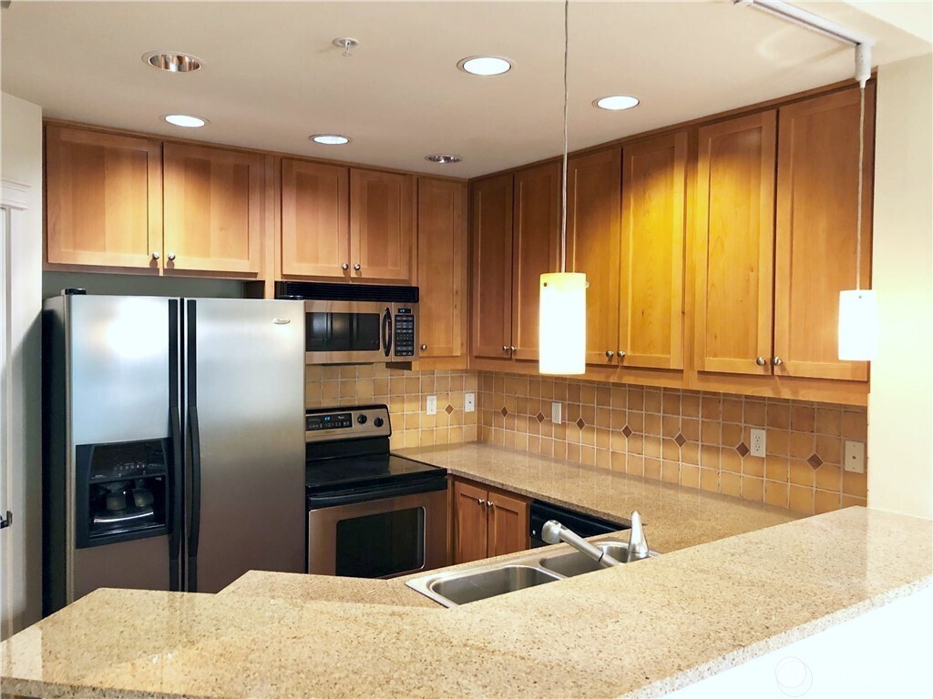 4321 Issaquah-Pine Lake Road Southeast, Unit 408 Sammamish, WA 98075 - Photo 6 of 33 a kitchen with granite countertop a refrigerator and a sink