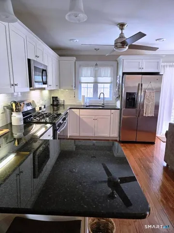 a kitchen with stainless steel appliances granite countertop a stove a sink dishwasher and a microwave oven with wooden floor