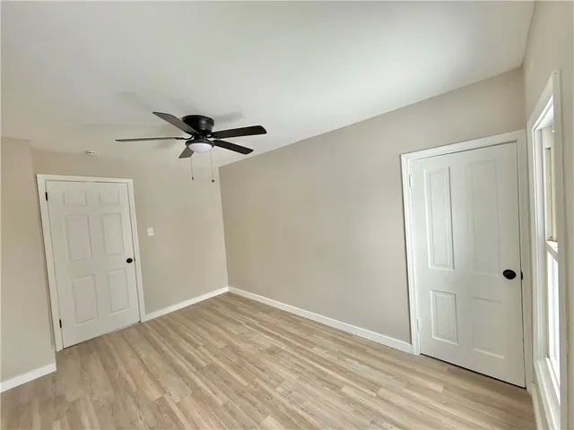 a view of empty room with wooden floor and ceiling fan