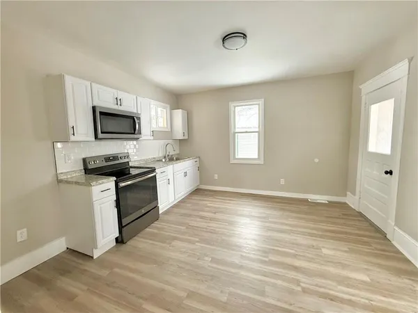 a kitchen with granite countertop a stove top oven a sink dishwasher a refrigerator and a microwave oven with wooden floor