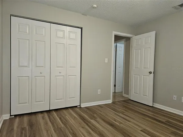 a view of an empty room with closet and wooden floor