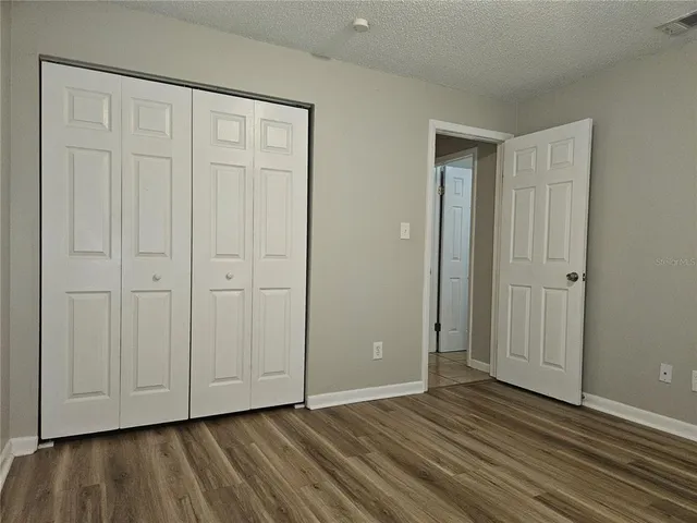 a view of an empty room with closet and wooden floor