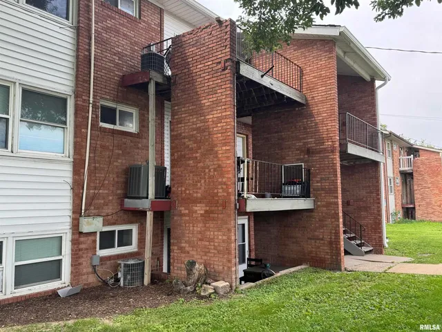 a view of a brick house with a yard and large tree