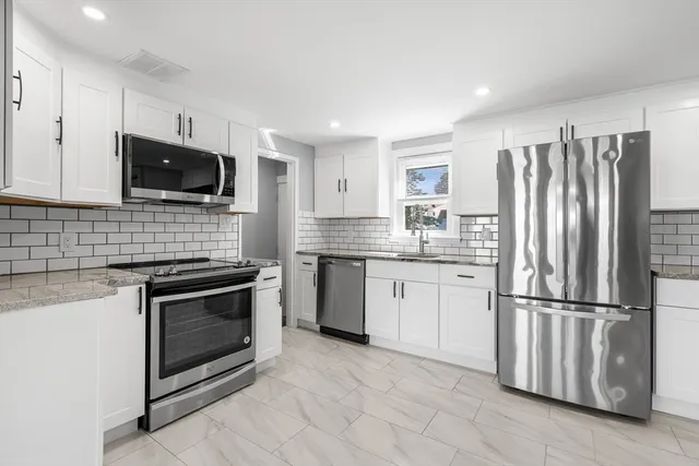 a kitchen with granite countertop a refrigerator stove and microwave