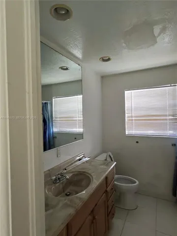 a bathroom with a granite countertop sink a toilet and a window
