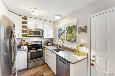 a kitchen with a sink white cabinets and stainless steel appliances
