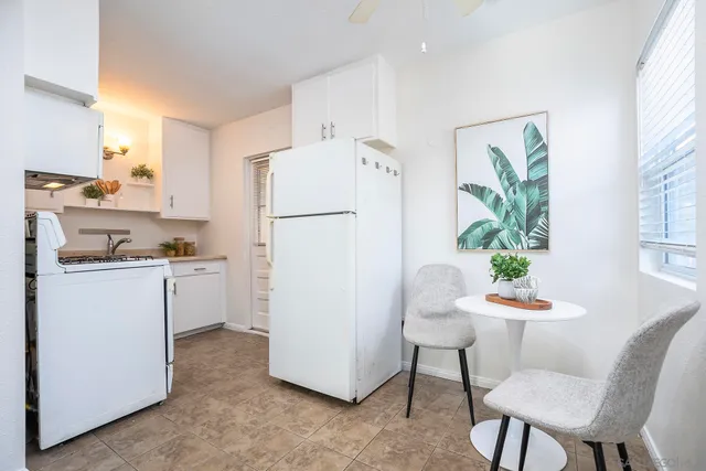 a kitchen with a refrigerator white table and chairs