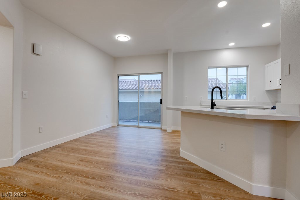 1881 West Alexander Road, Unit 1129 North Las Vegas, NV 89032 - Photo 16 of 31 Kitchen with white cabinets, light wood-style floors, recessed lighting, light stone countertops, and a kitchen breakfast bar