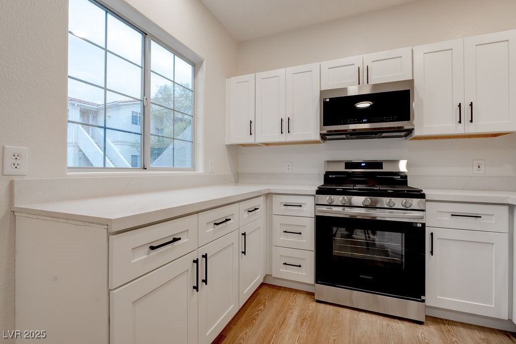 1881 West Alexander Road, Unit 1129 North Las Vegas, NV 89032 - Photo 18 of 31 Kitchen featuring appliances with stainless steel finishes, white cabinets, and light wood-style flooring