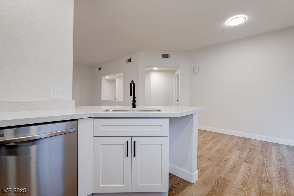 1881 West Alexander Road, Unit 1129 North Las Vegas, NV 89032 - Photo 20 of 31 Kitchen with dishwasher, white cabinets, a peninsula, light wood finished floors, and light stone counters