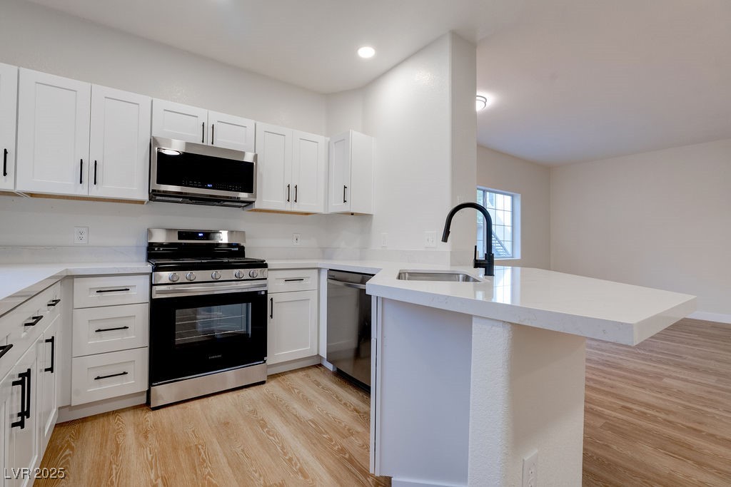 1881 West Alexander Road, Unit 1129 North Las Vegas, NV 89032 - Photo 3 of 31 Kitchen with stainless steel appliances, light wood finished floors, white cabinets, a peninsula, and recessed lighting