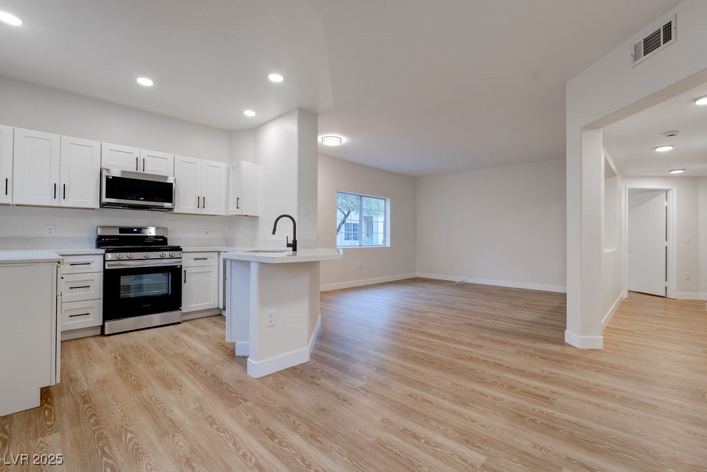 1881 West Alexander Road, Unit 1129 North Las Vegas, NV 89032 - Photo 31 of 31 Kitchen featuring recessed lighting, white cabinetry, appliances with stainless steel finishes, open floor plan, and light wood finished floors