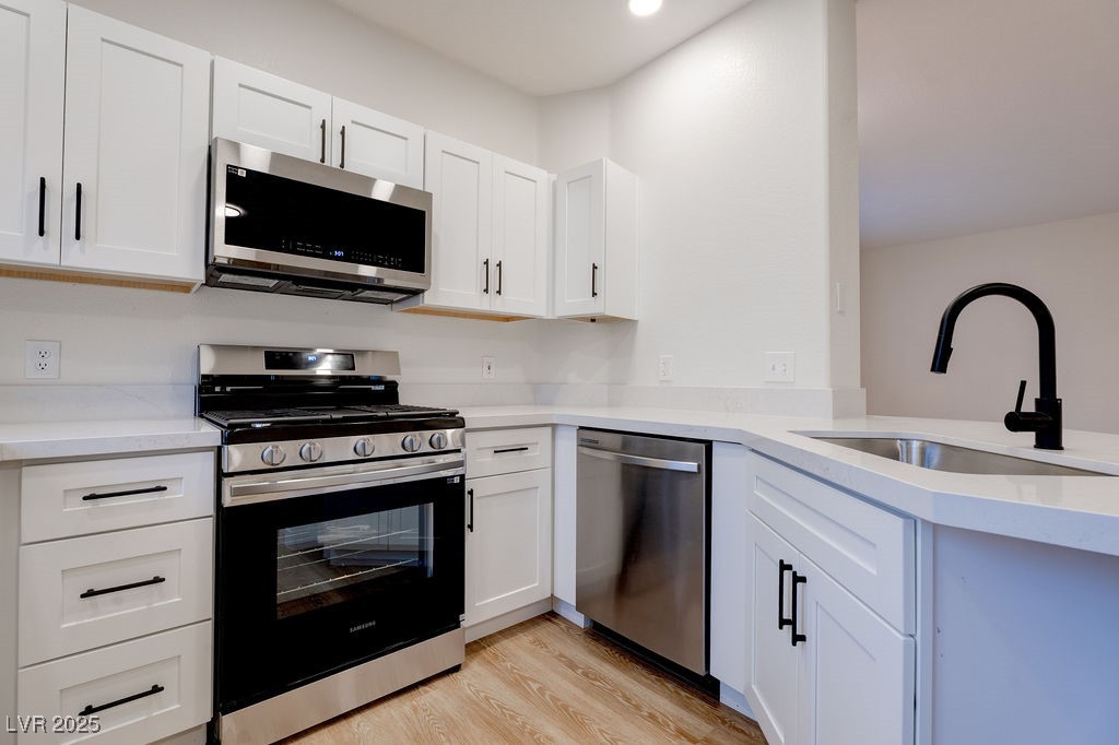 1881 West Alexander Road, Unit 1129 North Las Vegas, NV 89032 - Photo 4 of 31 Kitchen featuring appliances with stainless steel finishes, light wood-type flooring, white cabinetry, and light stone countertops
