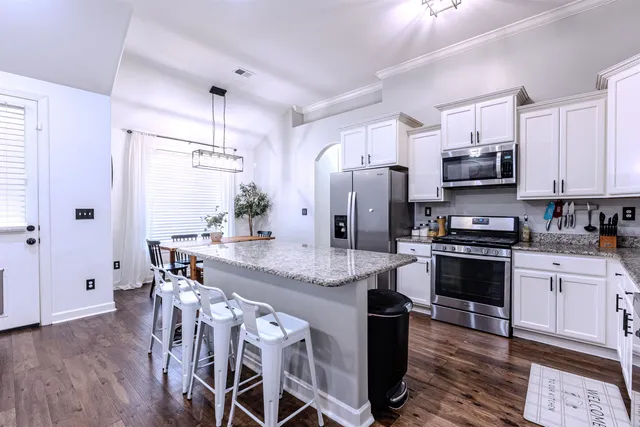 a kitchen with granite countertop white cabinets and stainless steel appliances