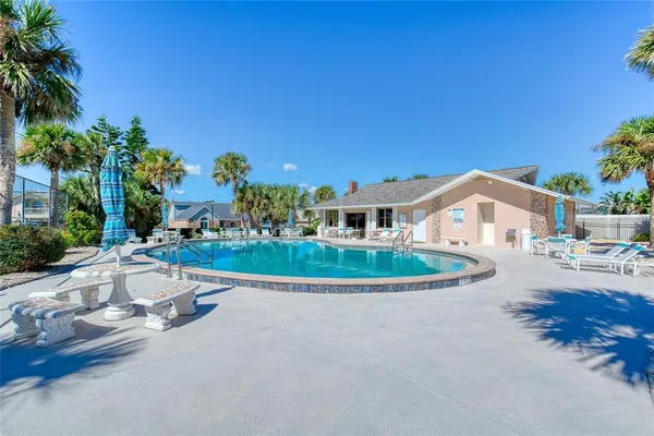 a view of a swimming pool with a yard and palm trees