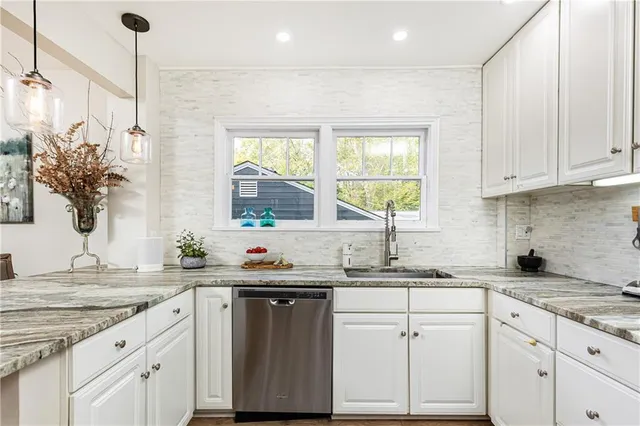 a kitchen with granite countertop a sink white cabinets and white appliances