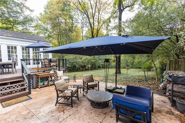 a view of a patio with couches chairs dining table and chairs under an umbrella