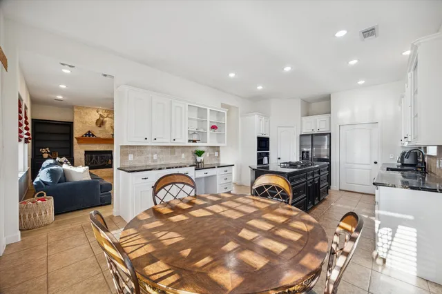 a view of kitchen with stainless steel appliances granite countertop a stove a sink a refrigerator and white cabinets with wooden floor