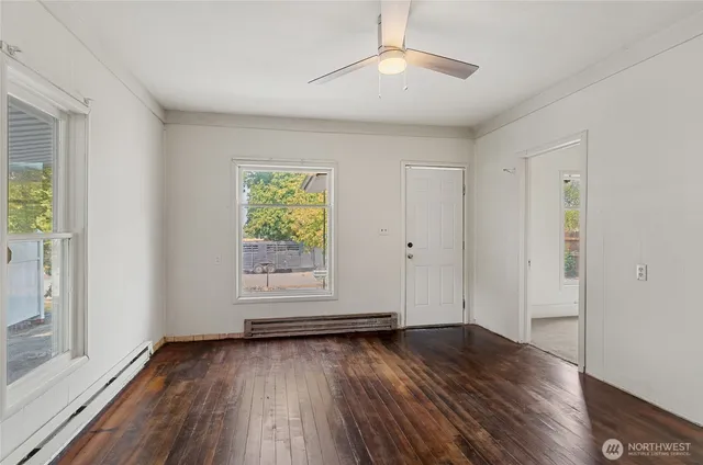 an empty room with wooden floor chandelier fan and windows