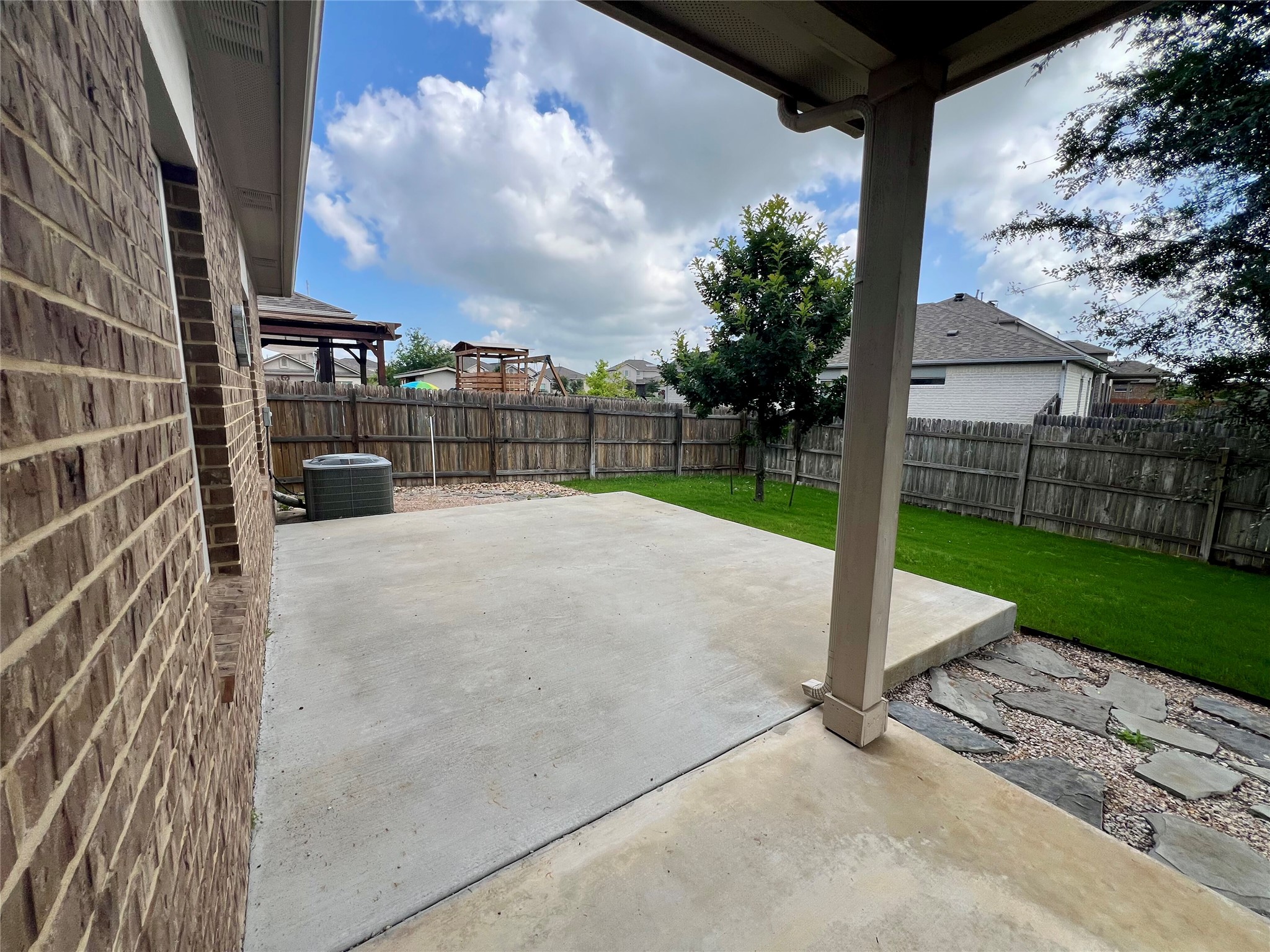104 Moravia Road Georgetown, TX 78626 - Photo 35 of 36 A spacious concrete patio awaits outdoor enjoyment, flanked by a neat lawn and mature trees.