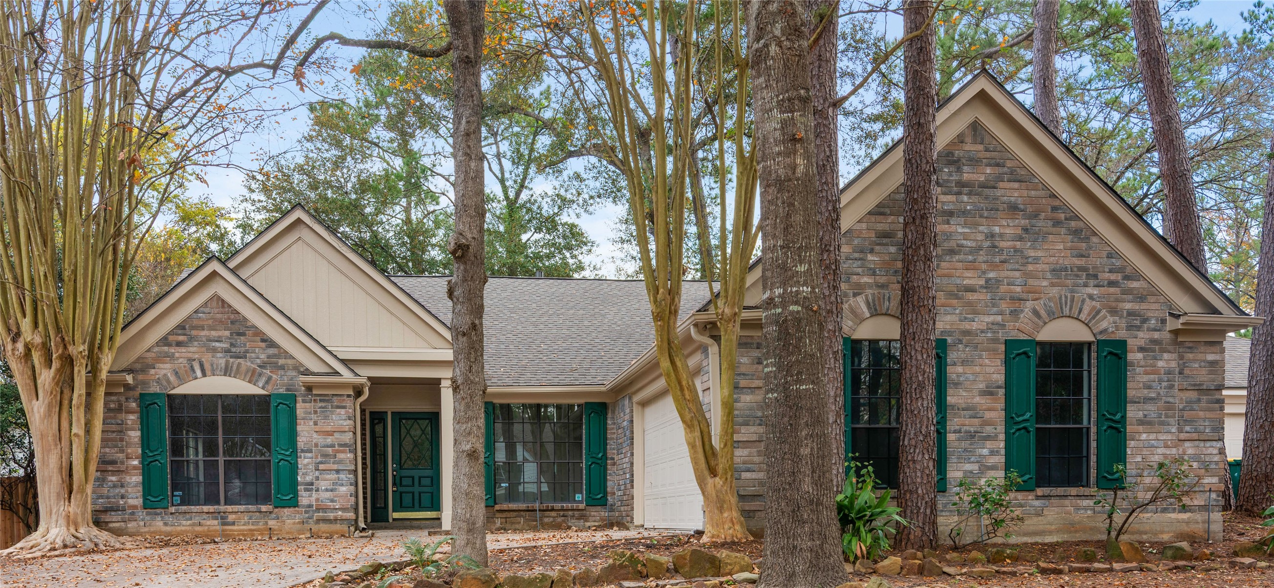10 White Fawn Drive Spring, TX 77381 - Photo 1 of 26 This charming single-story home features a brick exterior with elegant green shutters, nestled among mature trees. The front includes a welcoming porch and large windows, offering great natural light. The attached garage provides convenient access.