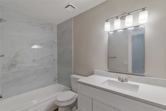 a bathroom with a granite countertop sink a toilet and shower