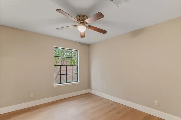 an empty room with windows and fan
