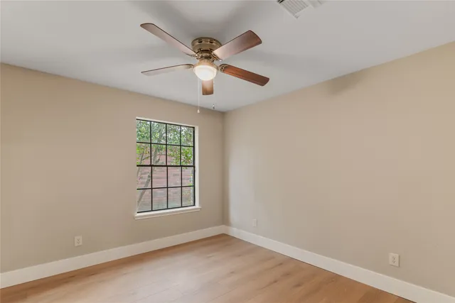 an empty room with windows and fan