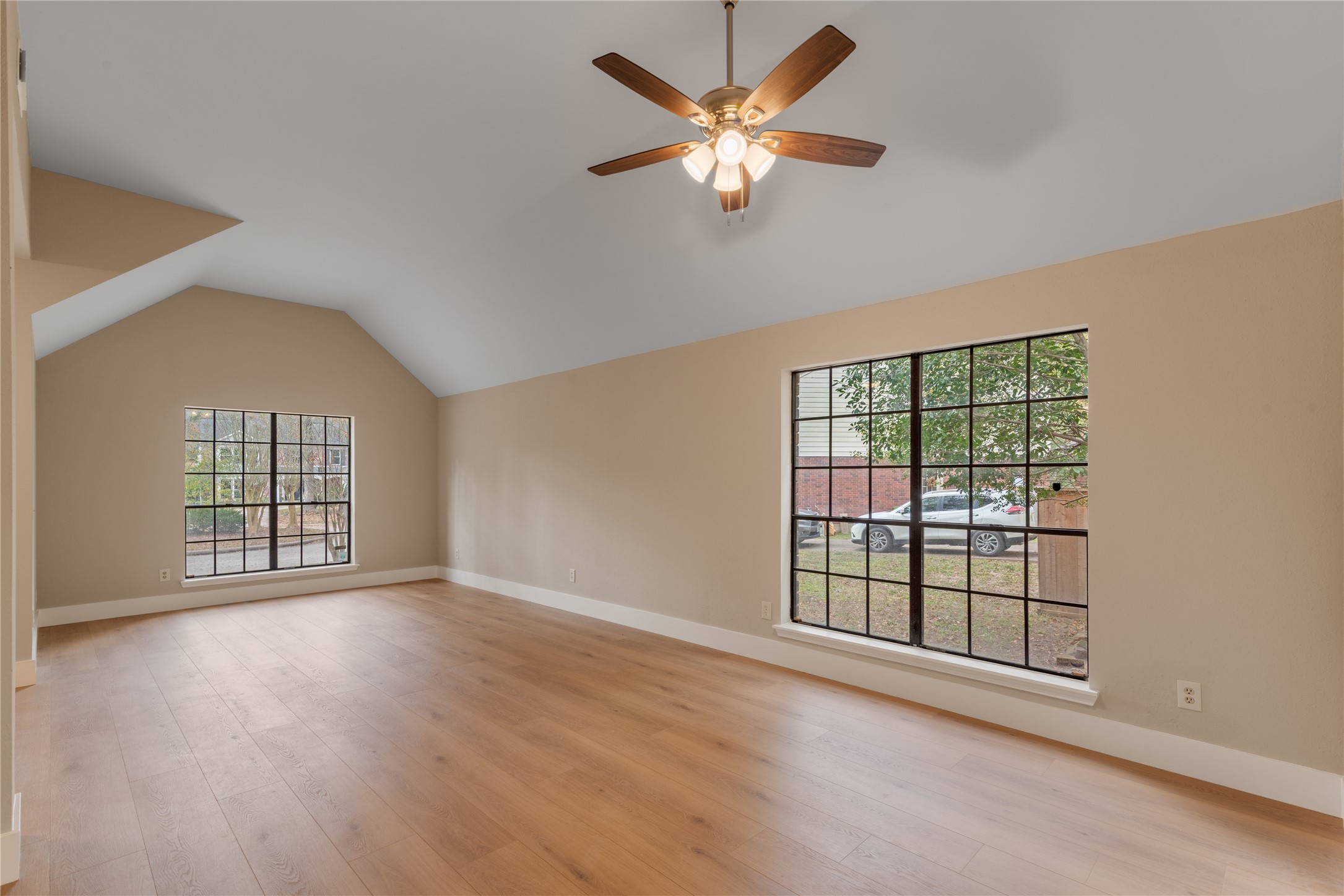 10 White Fawn Drive Spring, TX 77381 - Photo 5 of 26 This spacious room features vaulted ceilings, large windows for natural light, and beautiful wood flooring, creating an inviting and airy atmosphere.