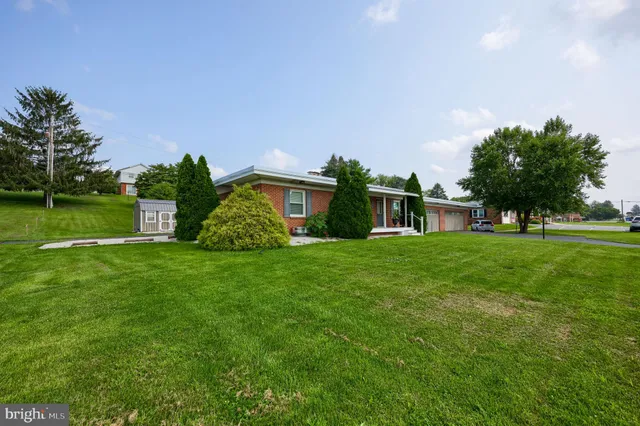 a view of a house with a yard and table and chairs under an umbrella