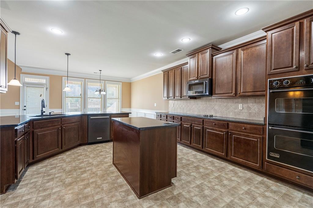 12 Juno Street Fort Mitchell, AL 36856 - Photo 9 of 43 Kitchen featuring a peninsula, black appliances, decorative backsplash, dark brown cabinets, and pendant lighting