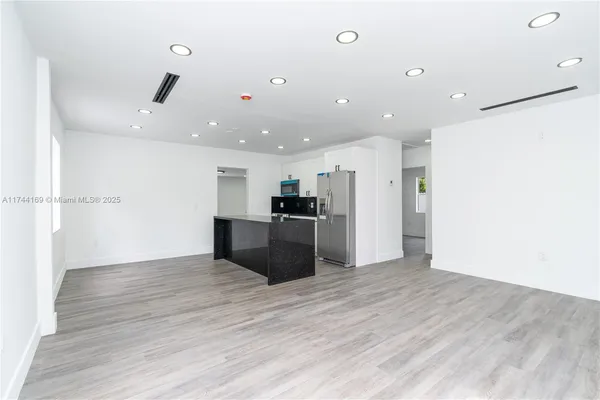 a kitchen with stainless steel appliances a refrigerator and wooden floor