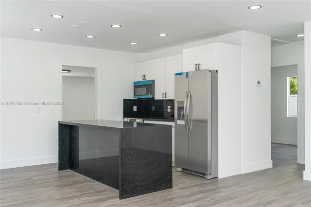 a kitchen with stainless steel appliances a refrigerator and wooden floor