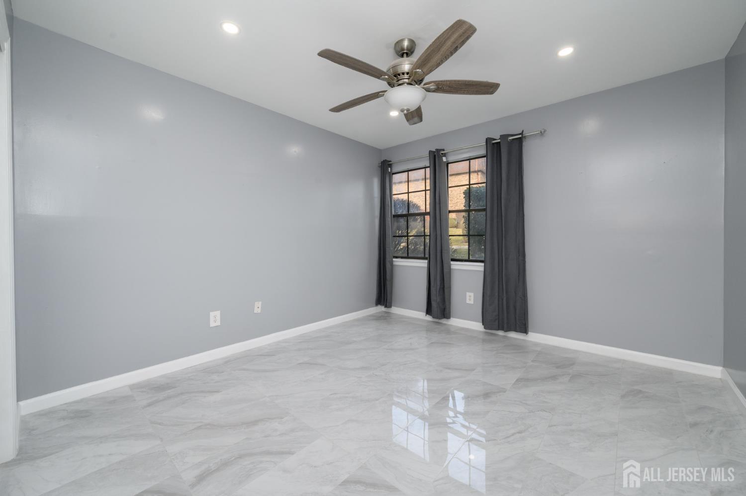 28 Powderhorn Court, Unit A Woodbridge, NJ 07095 - Photo 19 of 26 an empty room with windows and ceiling fan