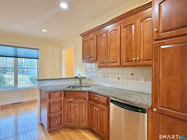 a kitchen with stainless steel appliances granite countertop a sink a stove cabinets and wooden floor