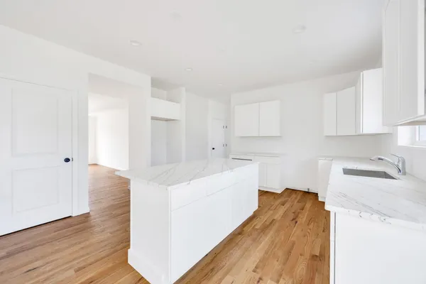 a kitchen with wooden floors and white cabinets