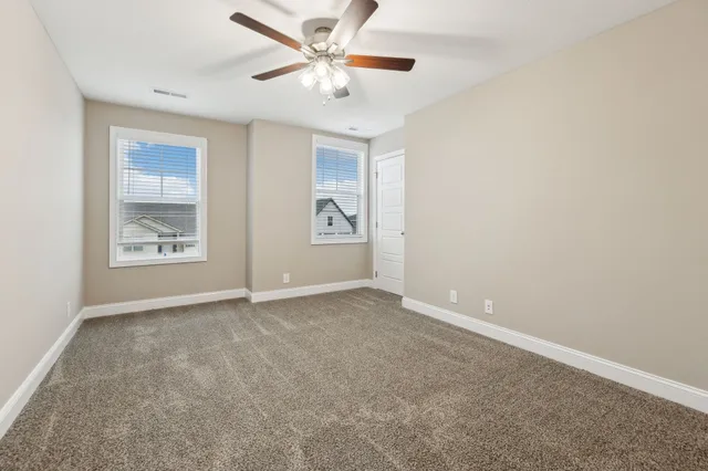 an empty room with closet and a ceiling fan