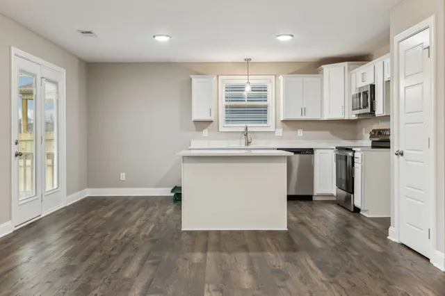 a kitchen with a sink stove cabinets and wooden floor