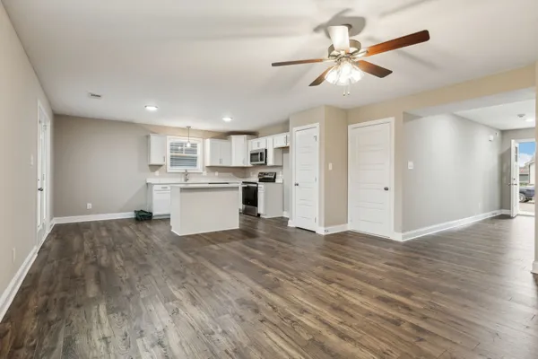 a kitchen with white cabinets and wooden floor