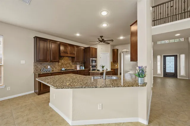a kitchen with stainless steel appliances granite countertop a sink a stove and a wooden cabinets
