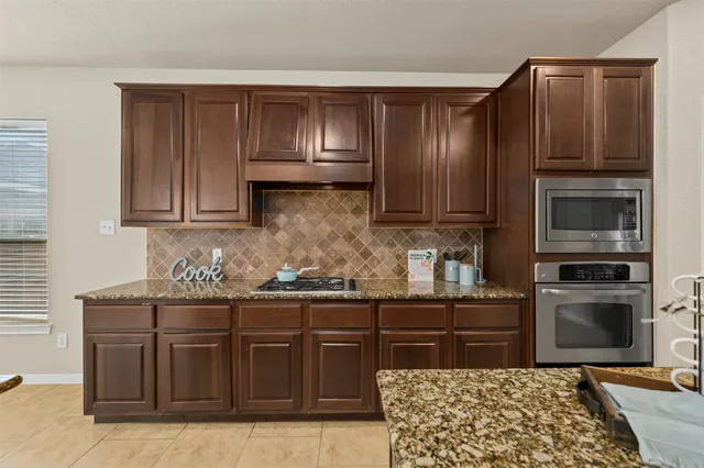 a kitchen with stainless steel appliances granite countertop wooden cabinets a stove top oven a sink and dishwasher