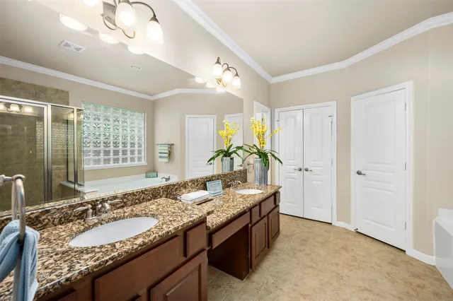 a spacious bathroom with a granite countertop double vanity sink a mirror and a shower
